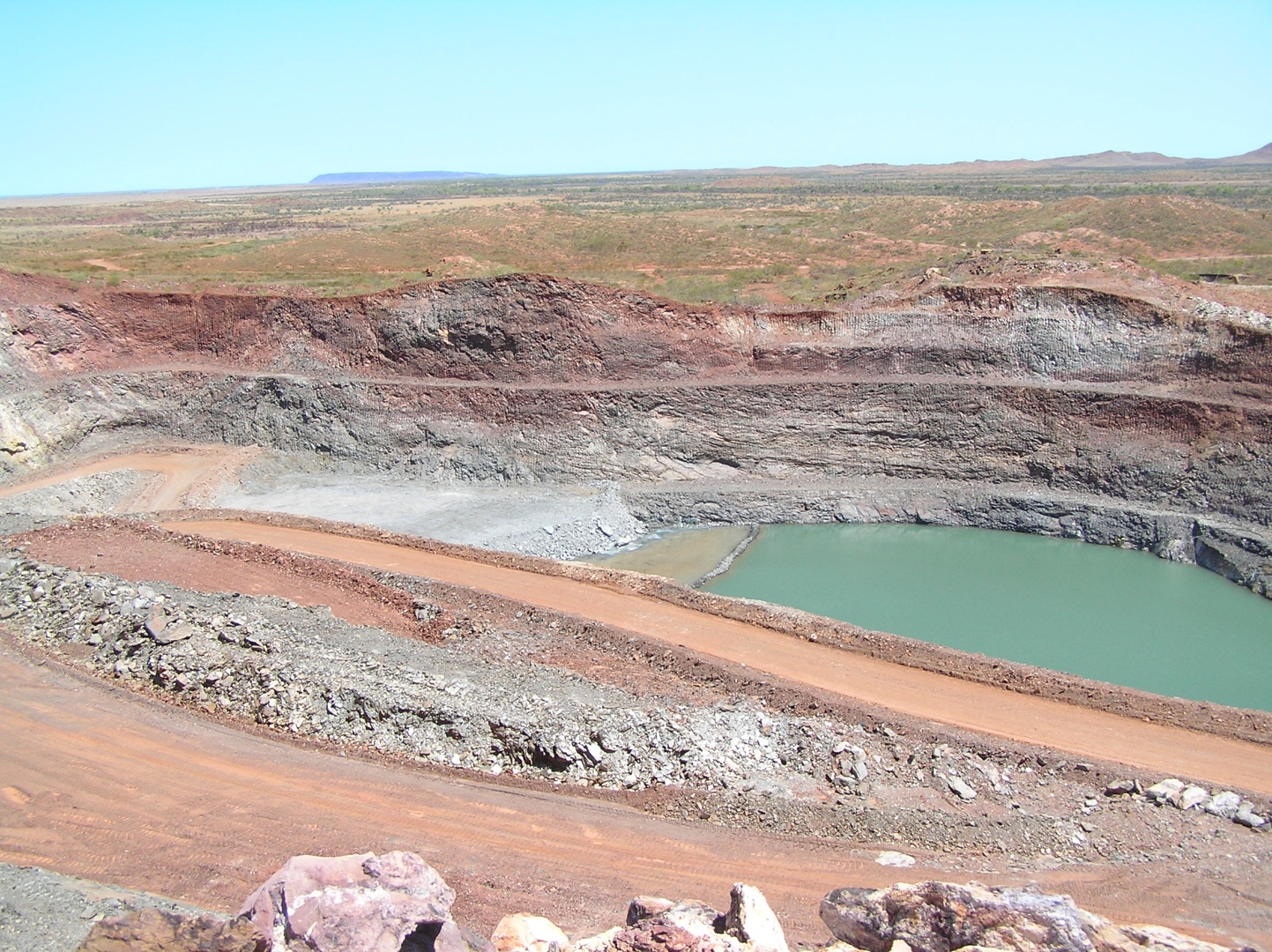 Open-cut pit and pit-water dam on a remote Australian mine site — representative of the kind of legacy mining environment managed under state contaminated-sites and mine-closure frameworks