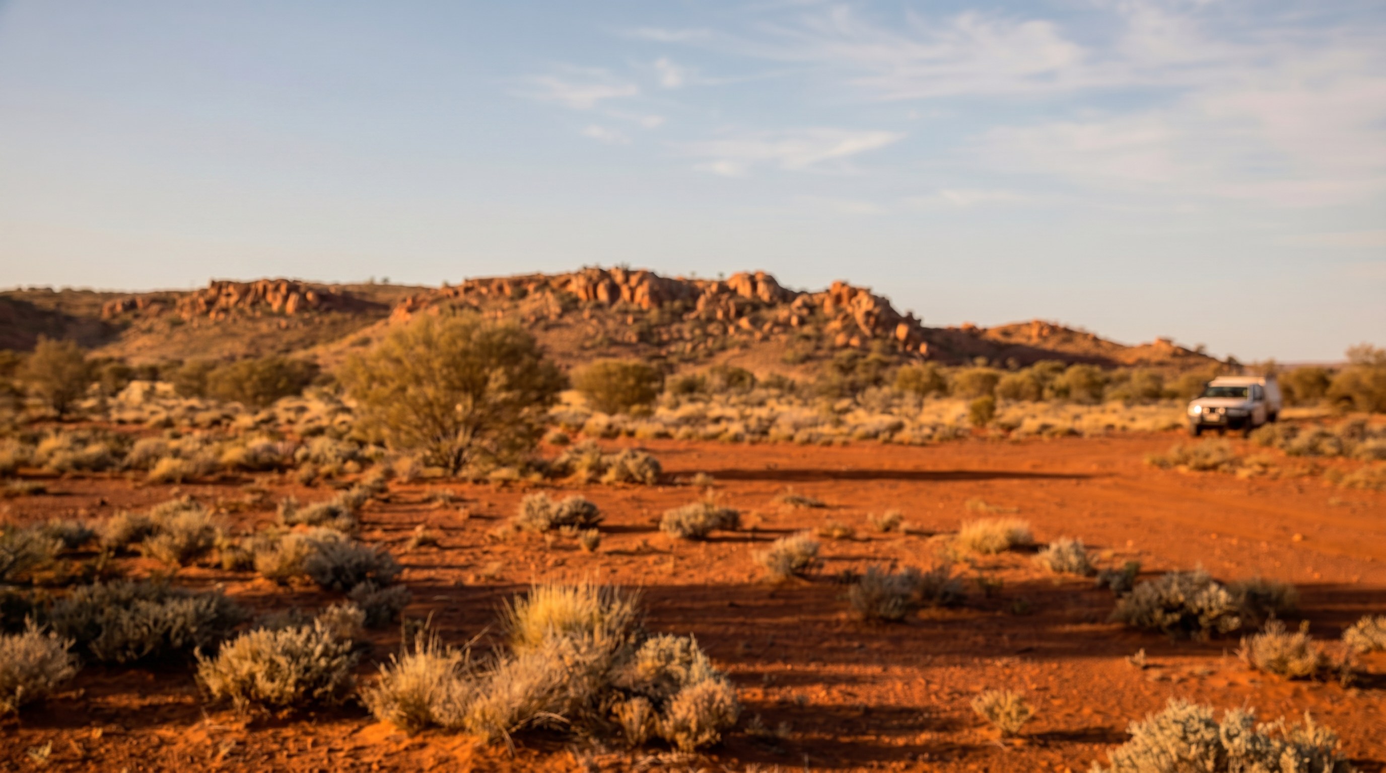 Senior mining compliance specialist reviewing a tenement map on Western Australian red-dirt country at golden hour